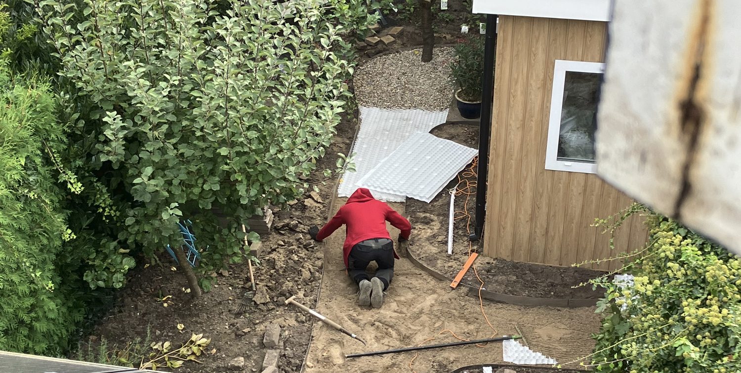 Aanleg tuinpad met zand, antiworteldoek, grindrooster en riviergrind Paul Naus legt een tuinpad aan